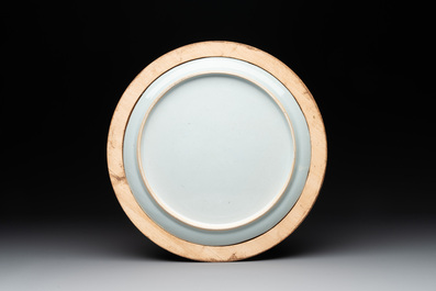 A Chinese famille rose plate with figures in a river landscape in gilt wooden frame, Yongzheng