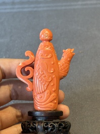 A Chinese carved red coral ewer and cover on wooden stand, 19th C.