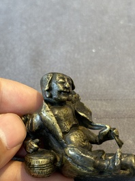 A Chinese bronze paperweight in the form of 'Shi De 拾得' on wooden stand, 16th C.