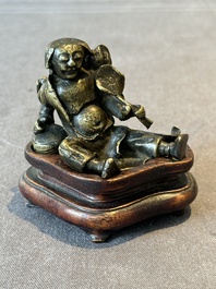 A Chinese bronze paperweight in the form of 'Shi De 拾得' on wooden stand, 16th C.