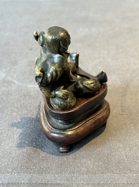 A Chinese bronze paperweight in the form of 'Shi De 拾得' on wooden stand, 16th C.