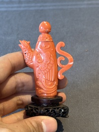 A Chinese carved red coral ewer and cover on wooden stand, 19th C.