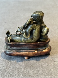 A Chinese bronze paperweight in the form of 'Shi De 拾得' on wooden stand, 16th C.