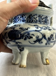 A Chinese blue and white tripod censer with floral design and a wooden cover, Ming