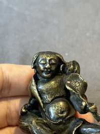 A Chinese bronze paperweight in the form of 'Shi De 拾得' on wooden stand, 16th C.