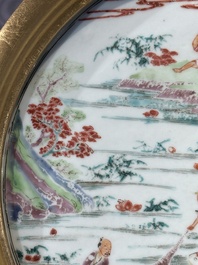 A Chinese famille rose plate with figures in a river landscape in gilt wooden frame, Yongzheng