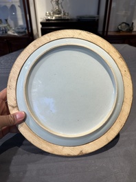 A Chinese famille rose plate with figures in a river landscape in gilt wooden frame, Yongzheng