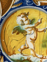 A polychrome Italian maiolica plate with a putto surrounded by trophies, Pesaro, 16th C.