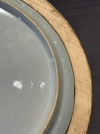A Chinese famille rose plate with figures in a river landscape in gilt wooden frame, Yongzheng