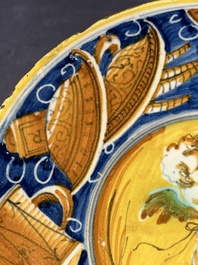 A polychrome Italian maiolica plate with a putto surrounded by trophies, Pesaro, 16th C.