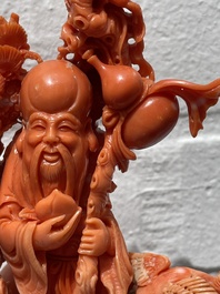 A Chinese red coral group of Shoulao with two boys holding a peach, inscribed 'Shou Bi Nan Shan 壽比南山', 19/20th C.