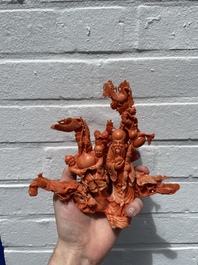 A Chinese red coral group of Shoulao with two boys holding a peach, inscribed 'Shou Bi Nan Shan 壽比南山', 19/20th C.