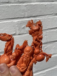 A Chinese red coral group of Shoulao with two boys holding a peach, inscribed 'Shou Bi Nan Shan 壽比南山', 19/20th C.