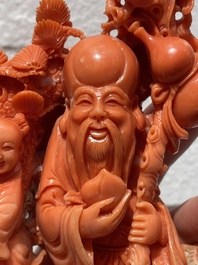 A Chinese red coral group of Shoulao with two boys holding a peach, inscribed 'Shou Bi Nan Shan 壽比南山', 19/20th C.