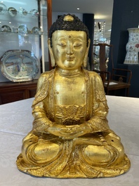 A large Sino-Tibetan gilt bronze Buddha on wooden stand, Ming