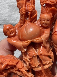A Chinese red coral group of Shoulao with two boys holding a peach, inscribed 'Shou Bi Nan Shan 壽比南山', 19/20th C.