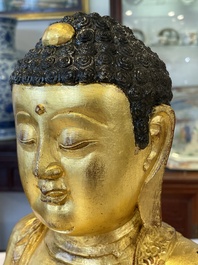 A large Sino-Tibetan gilt bronze Buddha on wooden stand, Ming