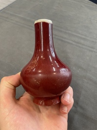 Two Chinese monochrome copper-red-glazed bottle vases on wooden stands, 19th C.