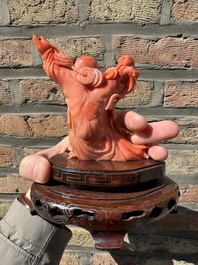 A Chinese red coral figure of a laughing Buddha on wooden stand, 19/20th C.