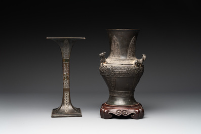 A Chinese archaistic bronze 'gu' vase and a 'hu' vase with rams in relief on a wooden stand, 18/19th C.
