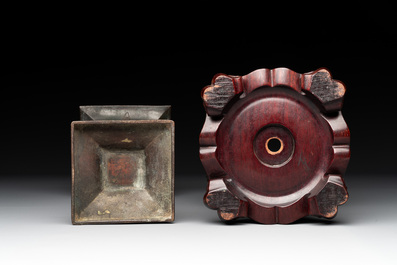 A Chinese archaistic bronze 'gu' vase and a 'hu' vase with rams in relief on a wooden stand, 18/19th C.
