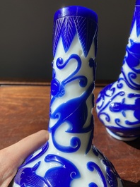 A pair of Chinese blue-overlay white Beijing glass 'chilong' bottle vases, 19th C.