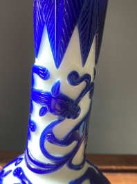 A pair of Chinese blue-overlay white Beijing glass 'chilong' bottle vases, 19th C.