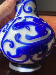 A pair of Chinese blue-overlay white Beijing glass 'chilong' bottle vases, 19th C.