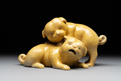 A Japanese monochrome yellow-glazed 'two playing dogs' group, 19th C.
