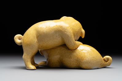A Japanese monochrome yellow-glazed 'two playing dogs' group, 19th C.