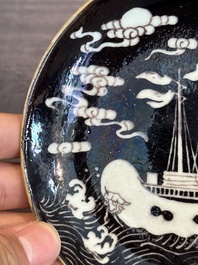 A Chinese iron-red 'bat' saucer and a black-glazed 'ship' saucer with calligraphy, Guangxu mark, 19th C.