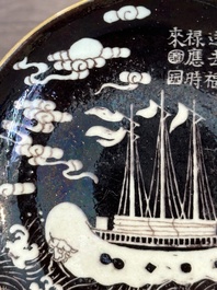 A Chinese iron-red 'bat' saucer and a black-glazed 'ship' saucer with calligraphy, Guangxu mark, 19th C.