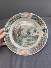A pair of Chinese famille verte plates with figures along the riverside, artemisia leaf and ding mark, Kangxi