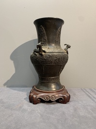 A Chinese archaistic bronze 'gu' vase and a 'hu' vase with rams in relief on a wooden stand, 18/19th C.