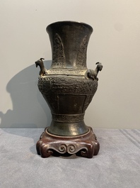 A Chinese archaistic bronze 'gu' vase and a 'hu' vase with rams in relief on a wooden stand, 18/19th C.