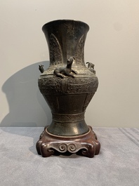 A Chinese archaistic bronze 'gu' vase and a 'hu' vase with rams in relief on a wooden stand, 18/19th C.