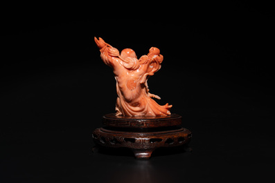A Chinese red coral figure of a laughing Buddha on wooden stand, 19/20th C.