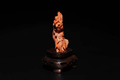A Chinese red coral figure of a laughing Buddha on wooden stand, 19/20th C.
