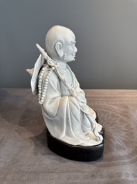 A Chinese Dehua blanc de Chine Luohan on wooden stand, 19/20th C.