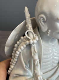 A Chinese Dehua blanc de Chine Luohan on wooden stand, 19/20th C.