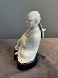 A Chinese Dehua blanc de Chine Luohan on wooden stand, 19/20th C.
