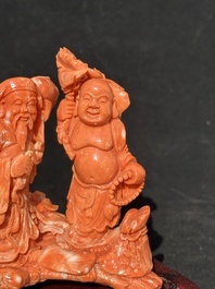 A Chinese red coral 'Sanxing' group on wooden stand, 19/20th C.
