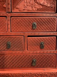 A Chinese cinnabar lacquer 'mountainous landscape' cabinet on a stand, 19th C.