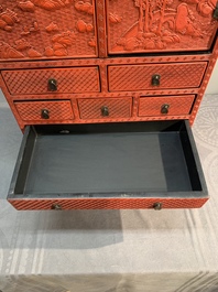 A Chinese cinnabar lacquer 'mountainous landscape' cabinet on a stand, 19th C.