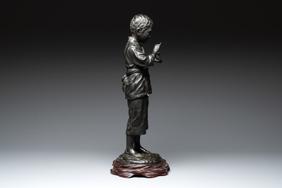 A Japanese bronze sculpture of a boy feeding a bird on a wooden stand, signed, Meiji, 19th C.