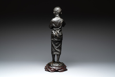 A Japanese bronze sculpture of a boy feeding a bird on a wooden stand, signed, Meiji, 19th C.