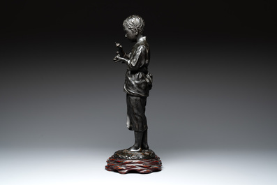 A Japanese bronze sculpture of a boy feeding a bird on a wooden stand, signed, Meiji, 19th C.