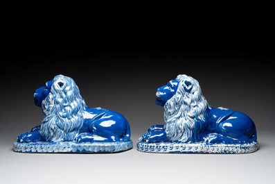 A pair of white-decorated blue-ground faience models of reclining lions, Nevers, 18th C.