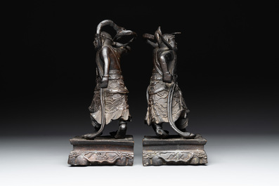 A pair of Chinese bronze guardians on stands, 17/18th C.