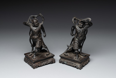 A pair of Chinese bronze guardians on stands, 17/18th C.